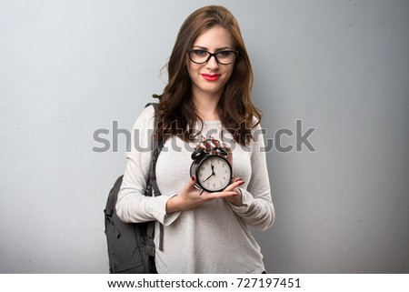 Student woman holding vintage clock on textured background