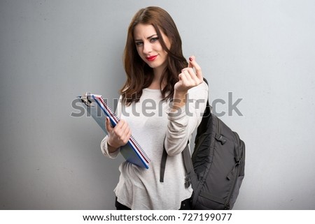 Student woman making money gesture on textured background