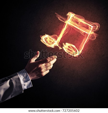 Close up of person hand and fire music symbol on dark background