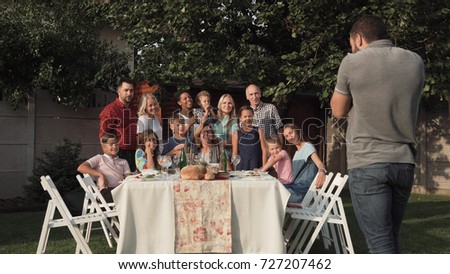 Cheerful family standing at table in garden and posing for photo.