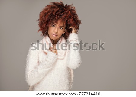 Happy beautiful african american girl with afro hairstyle posing in cozy sweater.