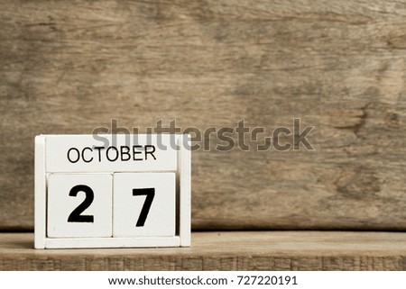 White block calendar present date 27 and month October on wood background