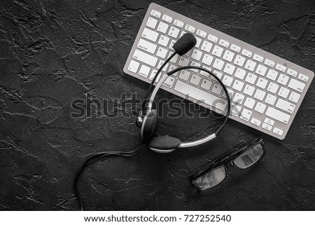 Call center manager's workplace. Headphones near keyboard on black background top view