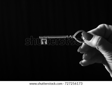 Hand giving keys on black background