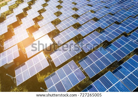 Top view of solar panels (solar cell) in solar farm with green tree and sun lighting reflect .Photovoltaic plant field. Royalty-Free Stock Photo #727265005