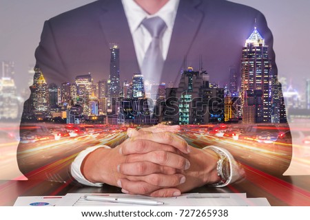 Double exposure of businessman fingers crossed and sit down,light trails on the street, urban and city in the night as meeting, commitment and business concept.