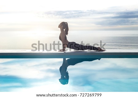 Vacation of Calm Attractive Asian woman practice yoga Cobra Pose on the pool above beach in the morning with beautiful sea in Tropical island,comfortable and relax in holiday.Yoga Vacations Concept Royalty-Free Stock Photo #727269799