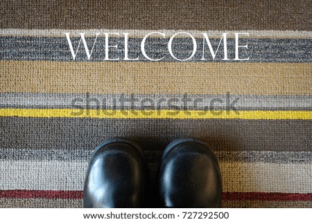 Welcome carpet with leather shoes on it.