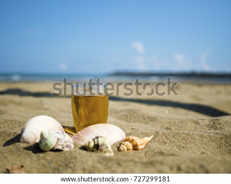 glass of tea with shells on summer beach