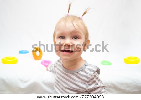 angry little girl is playing with a colored pyramid toy on a white isolated background