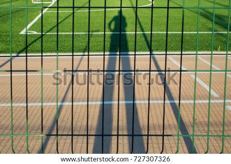 Want to play sports, person watching the Playground through the fence, shadow