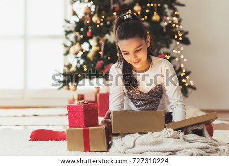 Cute girl opening a present on a Christmas morning 