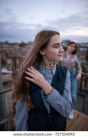 Young blonde with friend on cloudy sky background. Sisters, family, friendship relationships concept