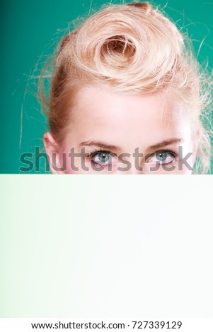 Woman standing behind white board at eye level, half face only. Studio shot on blue green background