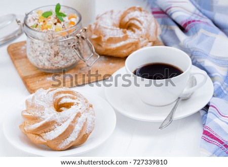 A cup of coffee, a granola, buns on a white background near a striped napkin