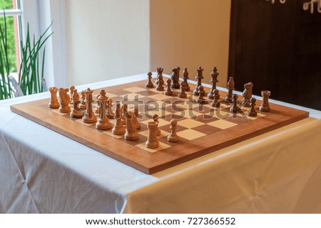 full chessboard with chess figures on table - intentionally dark