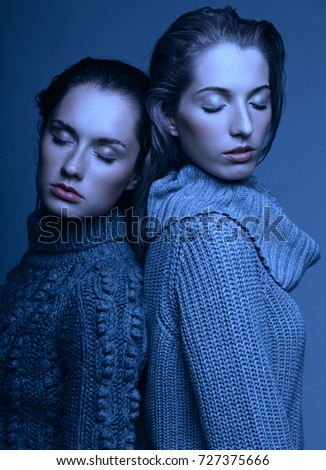 Halloween beauty portrait of two young women in gray sweaters on grey studio background. Beautiful girls stretching hands forward in embrace. Female friendship concept. Girls with hands closed