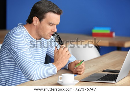 Young man holding credit card while using laptop at home