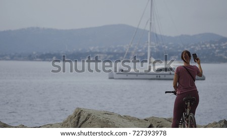 woman posing on a bicycle and takes photo of the landscape of the seashore