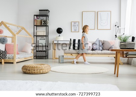 Black globe on white desk next to shelf with patterned boxes and grey bag in girly bedroom