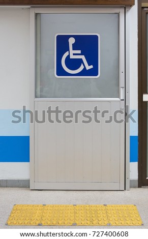 Aluminium door with sign for disabled people with yellow Tactile paving 