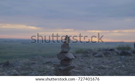 Pebbles tower Zen and balance. Stack of the pebbles against the sky. Tower of stones on the background of the field and the morning sky