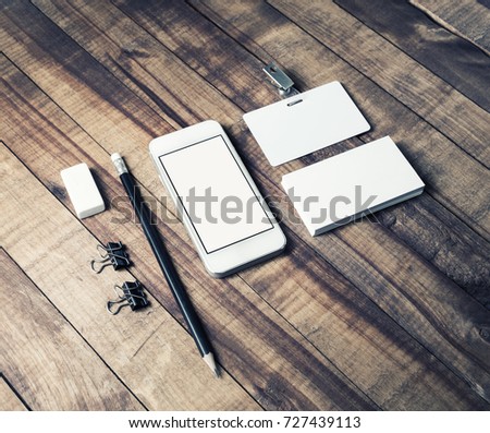 Smartphone, business cards, badge, pencil and eraser on wooden table background. Mock up for graphic designers portfolios. Responsive design template.