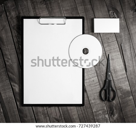 Photo of blank corporate stationery on wood table background. Blank paper, clipboard, business card, cd and scissors. Top view.
