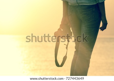 silhouette relax woman travel photographer hold camera in sunset flare at sea and horizon with copy space in travel and fashion concept 