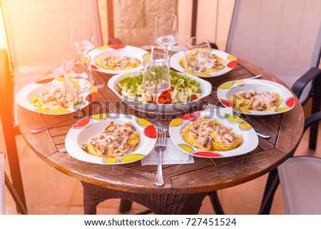 Pasta with mussels, vegetable salad and wine glasses on a round wooden table