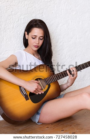Charming Young Woman playing Acoustic Guitar
