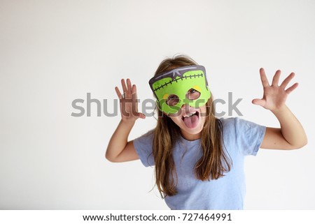The girl plays the fool in a mask of the monster for the holiday Halloween Royalty-Free Stock Photo #727464991