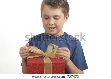 Young boy in t-shirt opening (or wrapping) a red and gold present