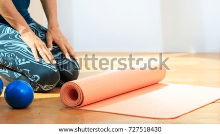 Fitness at home concept. Woman and an exercise mat on wooden floor. Copy space