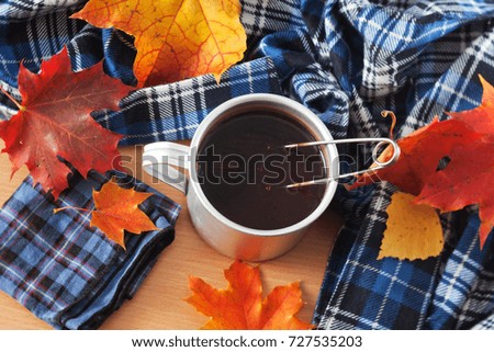 Tea mug, handkerchief and autumn leaves on the table
