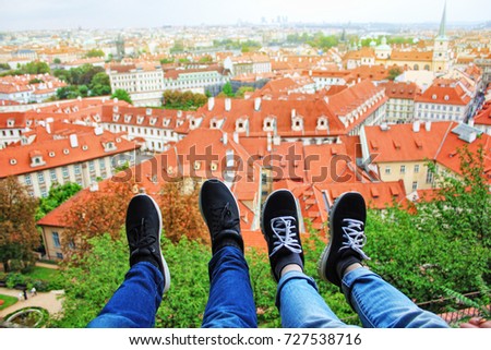 Male and female legs in the background of roofs of Prague city Czech republic on a sunny summer day. Typical Prague houses.