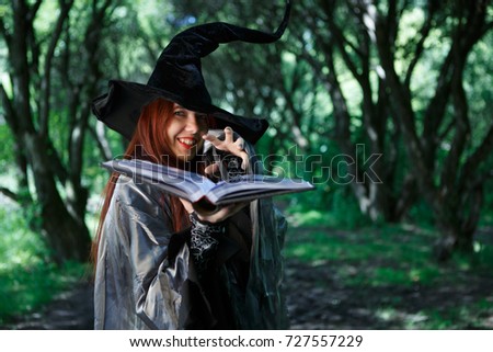 Image of young laughing witch with book