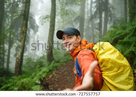Photo of young man with backpack stretching arm