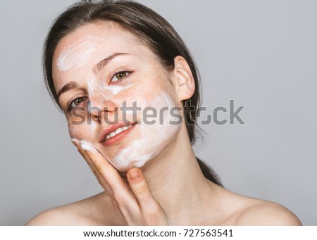 Young beautiful woman washing her face with hands by soap. Studio shot