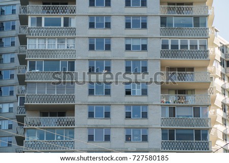 Exterior day time establishing photo of a generic tall apartment building with balcony facade