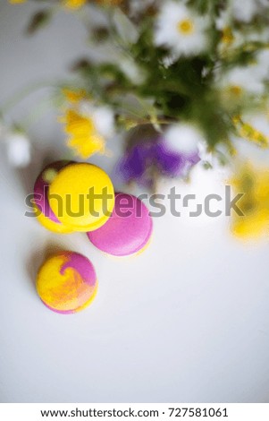 colourful macaroons on a white table with flowers