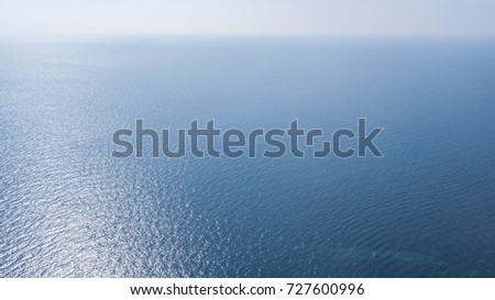 Aerial view of the blue ocean surface of the Atlantic Ocean. The sun, above the horizon, reflects its sunlight on the sea. Royalty-Free Stock Photo #727600996