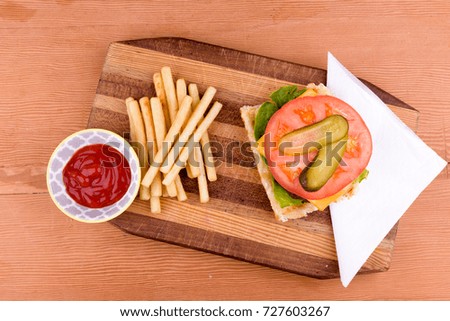 Bruschetta with hamburger with cheese, lettuce, tomato and pickle with a side of fries on a chopping board