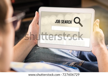Man trying to find work with online job search engine on tablet. Jobseeker at home holding smart device. Motivated and happy applicant. Modern job hunting, seeking and unemployment concept. Royalty-Free Stock Photo #727606729