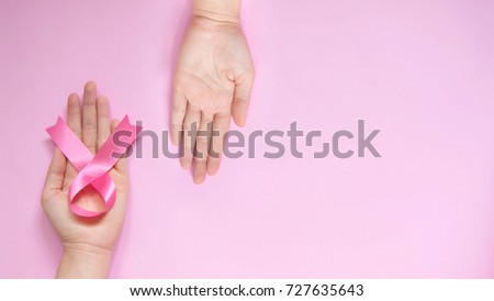 Breast cancer survivor hands giving satin pink ribbon awareness to naive patient for help women w/ breast cancer/tumor on pink background. Healthcare and medical concept. October pink day. Copy space. Royalty-Free Stock Photo #727635643