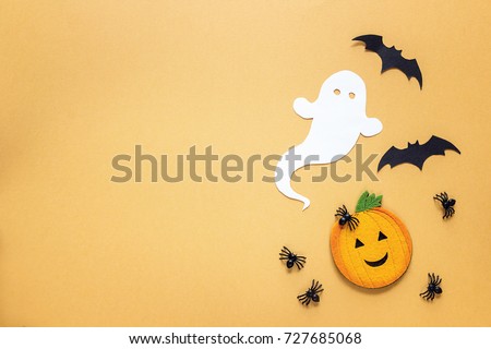 Flat lay Halloween background with decorative pumpkin, ghost, spiders and bats on orange backdrop. Copy space for text. Festive  concept. 