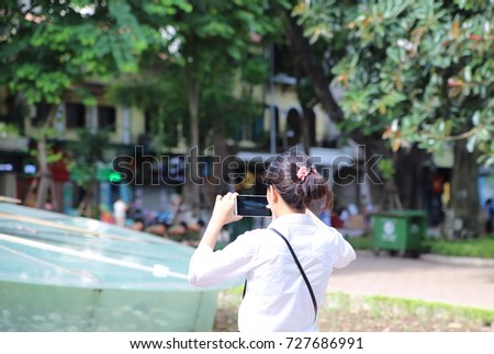 Young woman taking photos by smartphone in Hanoi