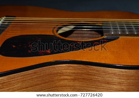 Closeup photo of a child's acoustic guitar body and sound hole and pic guard 