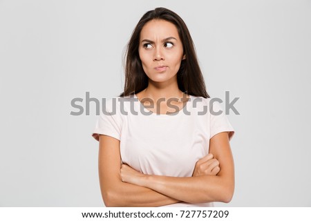 Portrait of an upset unsatisfied asian woman standing with arms folded and looking away isolated over white background Royalty-Free Stock Photo #727757209