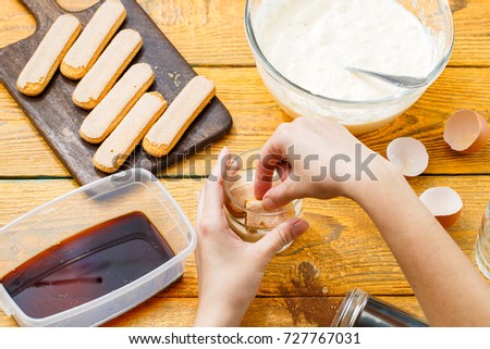 Photo of wooden table with biscuits, coffee, cream cheese, eggshells, human hands